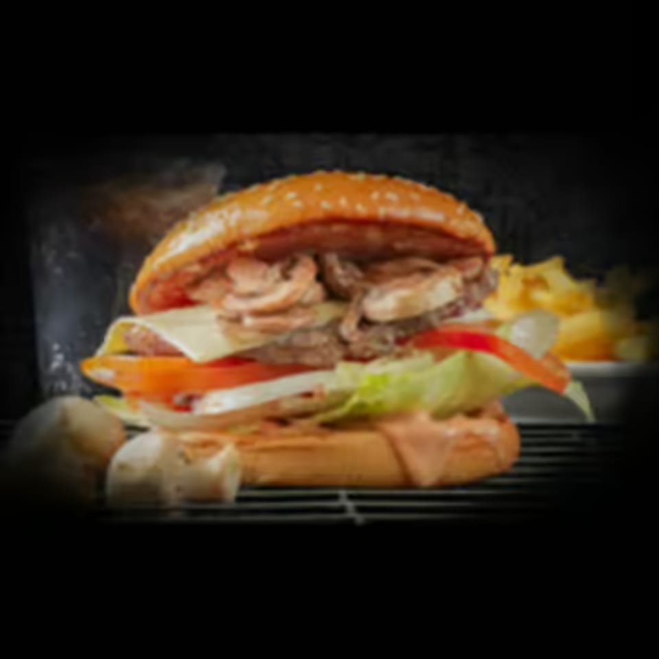 Gourmet mushroom burger with cheese, lettuce, tomato, and sauce, served with fries.