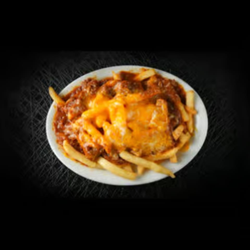 A white plate piled high with golden french fries, smothered in chili and melted cheese.
