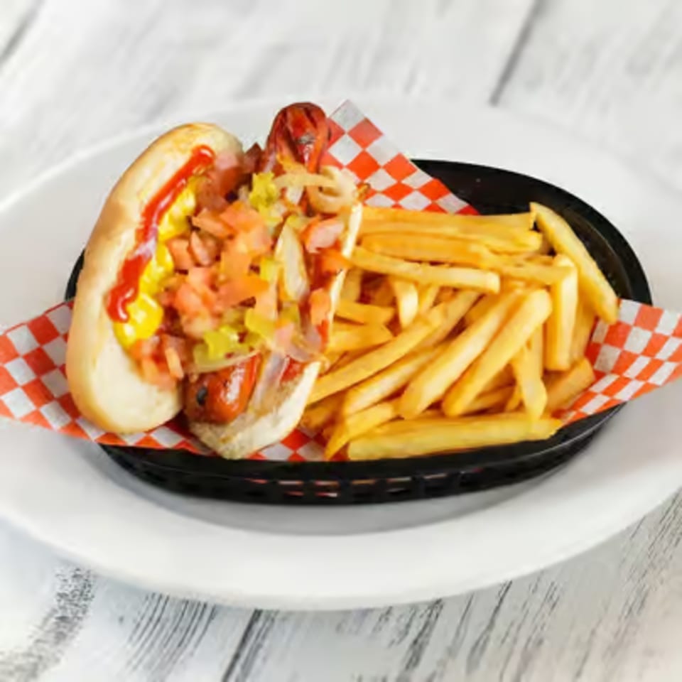 Hot dog with ketchup, mustard, relish, and onions, served with a side of french fries.